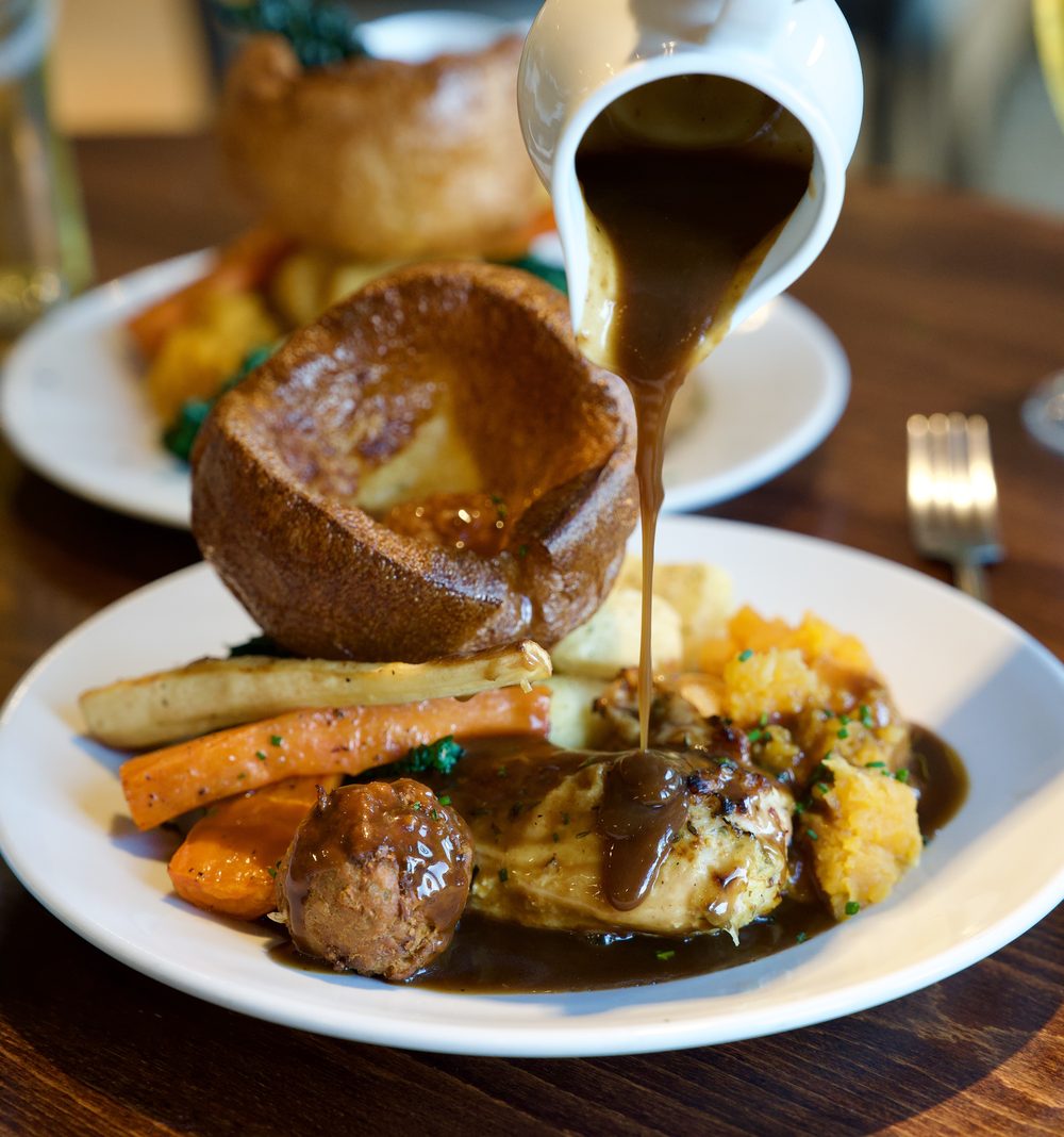 Gravy poured from a jug over a Sunday roast at The Foundry: chicken and stuffing with a Yorkshire pudding, roast potatoes, carrots, parsnips and kale